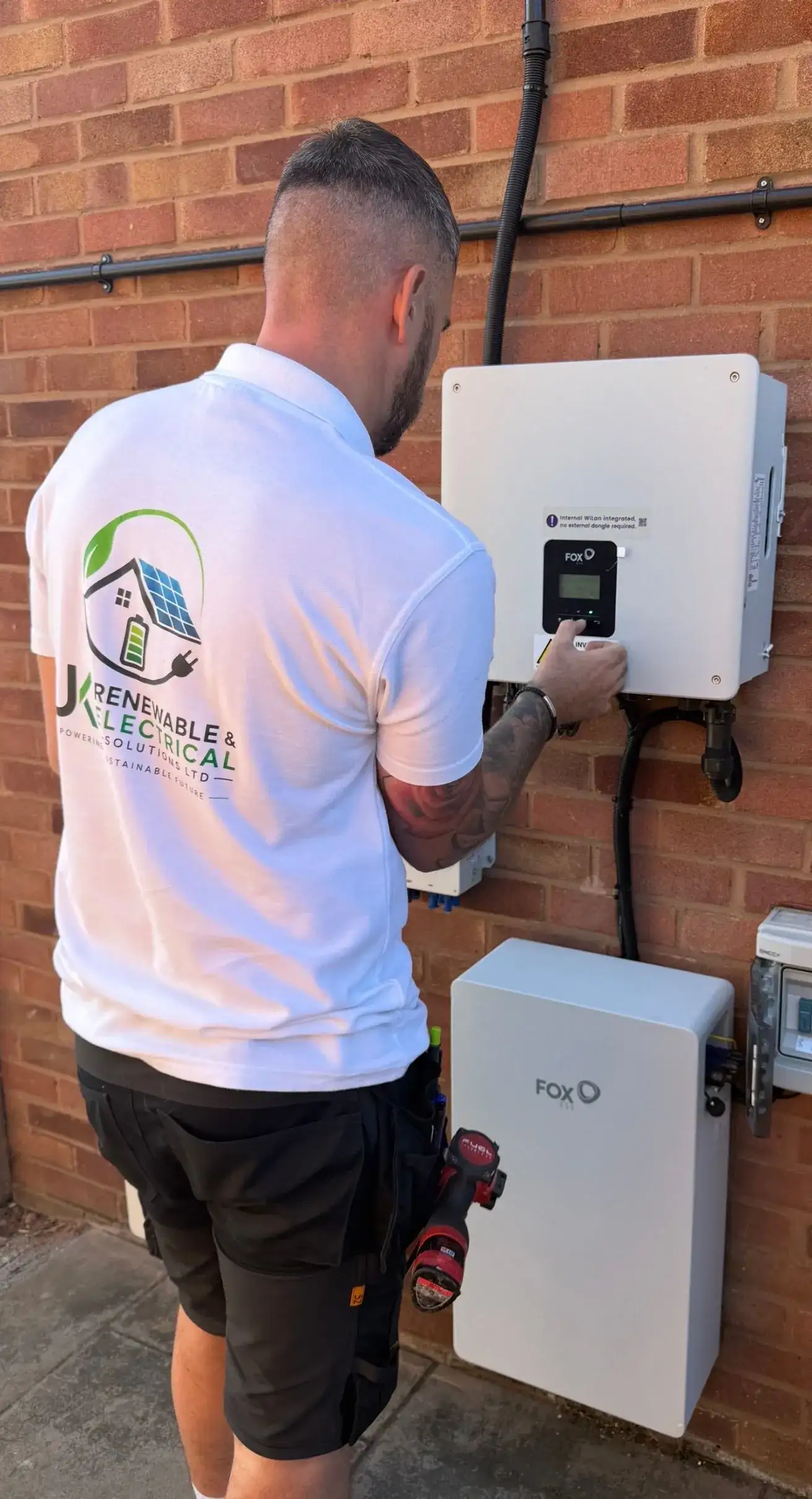 Electrician checking a Fox battery system beside a completed meter cupboard installation